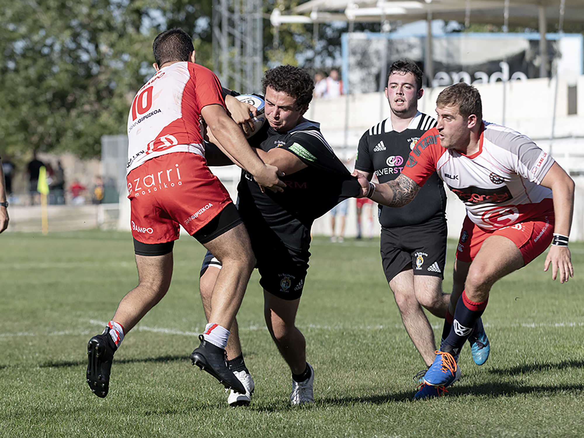 Foto JL Useros: Fernando Romanos es frenado por dos rivales en el encuentro entre SilverStorm El Salvador Emerging y Moyua Goierri de la pasada temporada en los campos de Pepe Rojo.